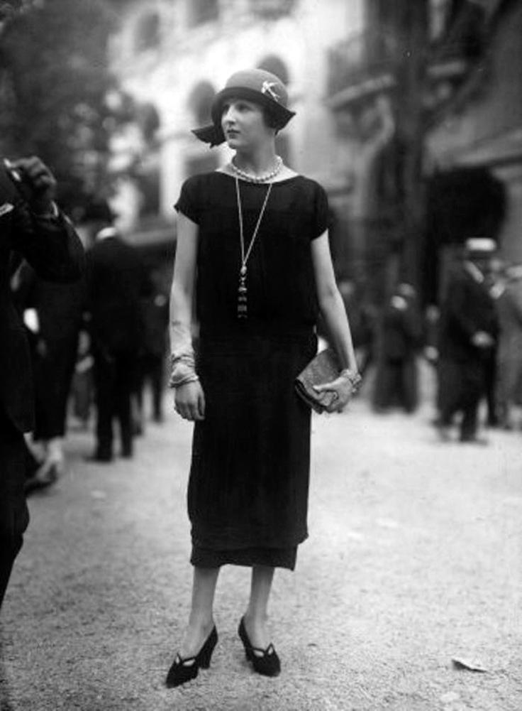 A black dress tapering in slightly at the hem, including a front panel decorated with tiny pleats. Designed by Jenny. Seeberger Freres on Getty Images